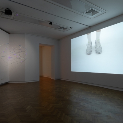 Widok na wystawę "Zwichnięty czas", fot. A. Zagrodzka: przestrzeń wystwy, po lewej stronie ściana na której za pomocą projektora są wyświetlane obrazy