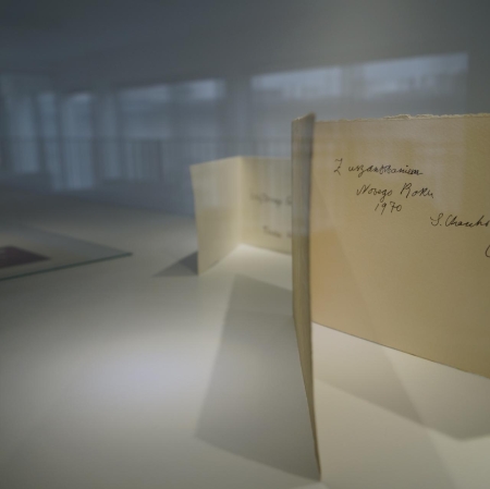 Fragment wystawy. Na pierwszym planie otwarta pocztówka z dedykacją.