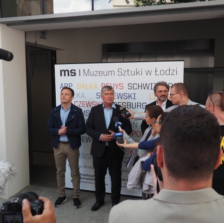 People standing in front of microphones, other people around
