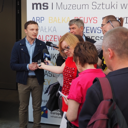 People standing in front of microphones, other people around