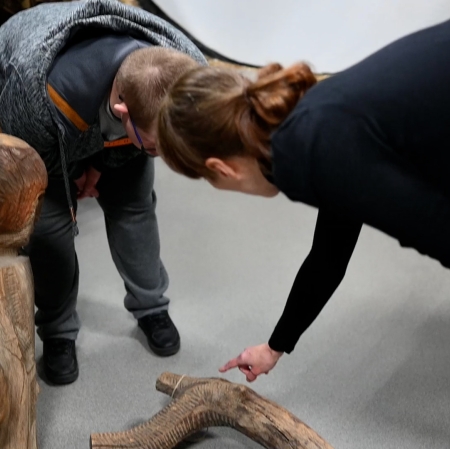 People leaning over a sculpture lying on the floor