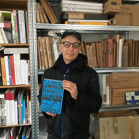 A person holding a book in his hands, with bookshelves in the background