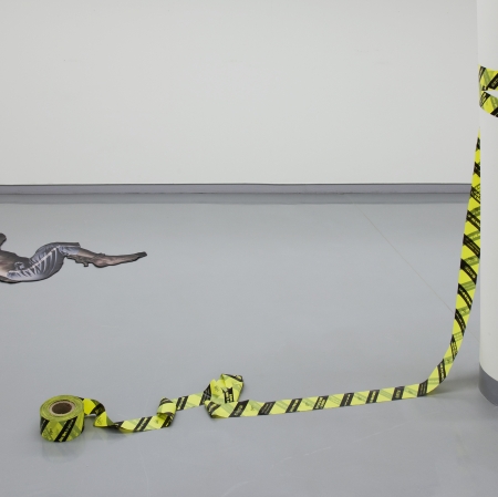 Artwork, printes on the floor drawing of a man and tape in yellow and black stripes, tangled around pole