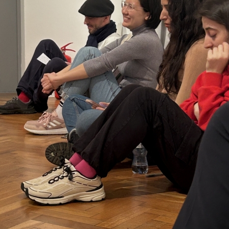 several people are sitting leaning against the wall, some girl are smiling