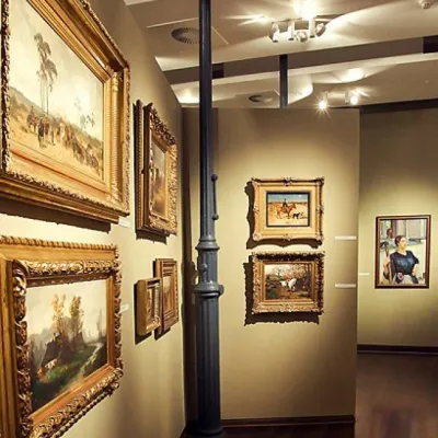 Wycinek galerii z obrazami w zdobionych ramach 