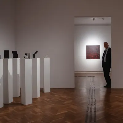 The exhibition space, white walls, visible sculptures and paintings